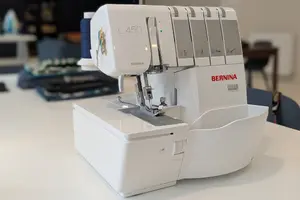 Surjeteuse Bernina L450 sur une table, prête à coudre, avec bobine de fil bleue.
