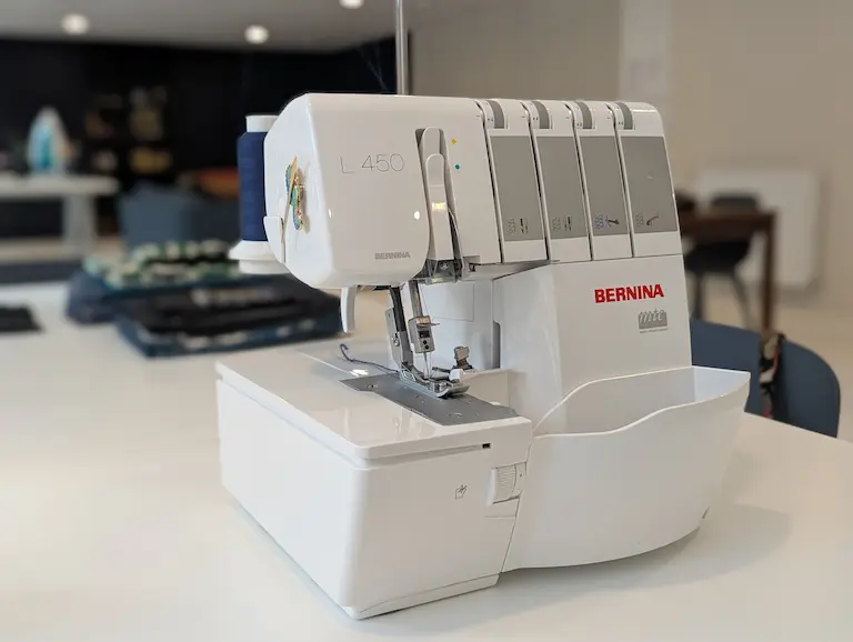Surjeteuse Bernina L450 sur une table, prête à coudre, avec bobine de fil bleue.